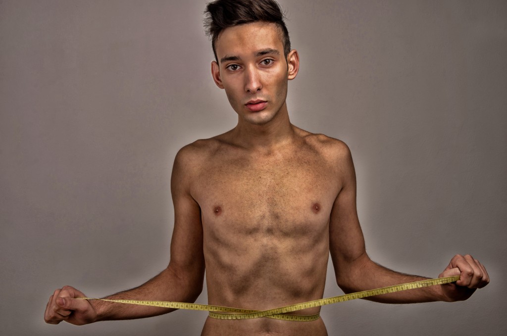 man with anorexia measuring his waist