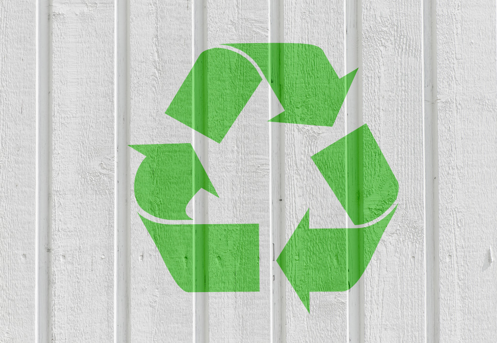 Recycling symbol on white wooden wall background.