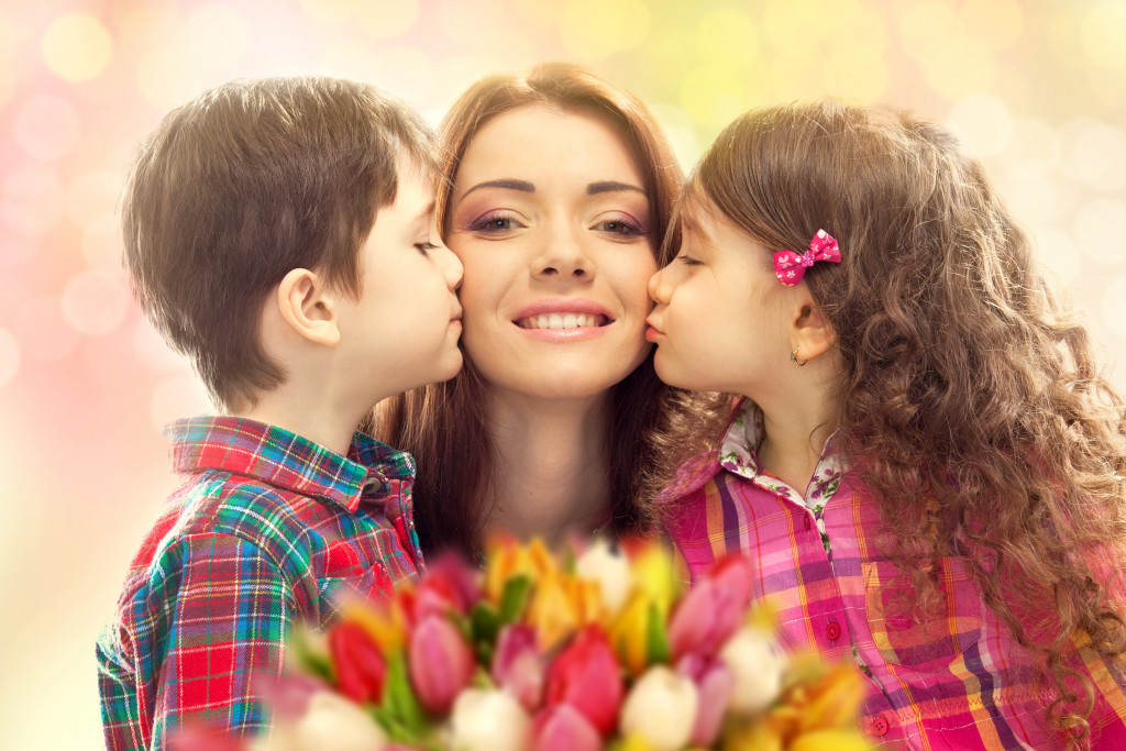 woman being kissed in both cheeks by her children