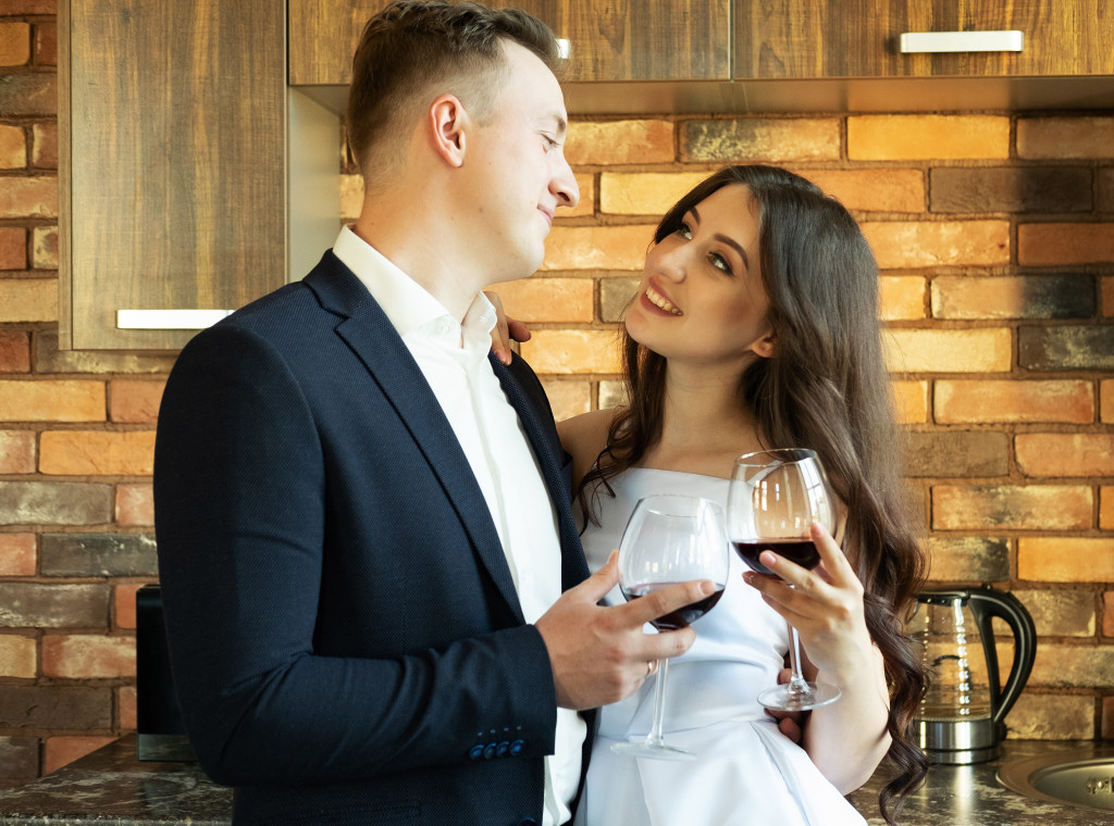 Young newlywed couple drinking wine and smiling at their happiness, romance and tenderness