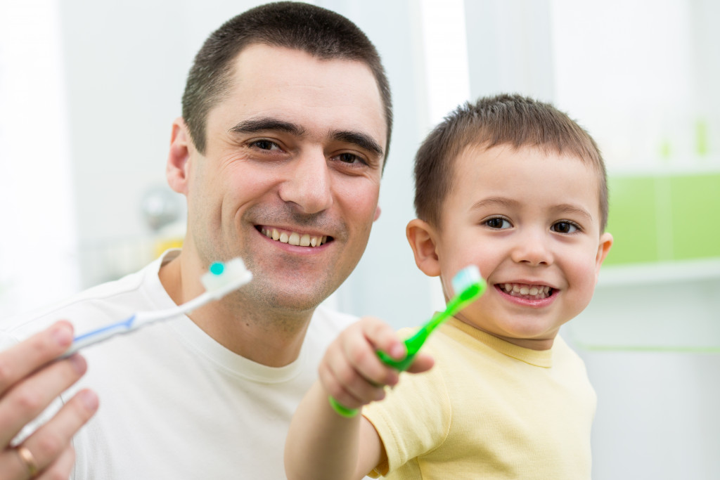 Portrait of a man teaching his son brushing teeth 