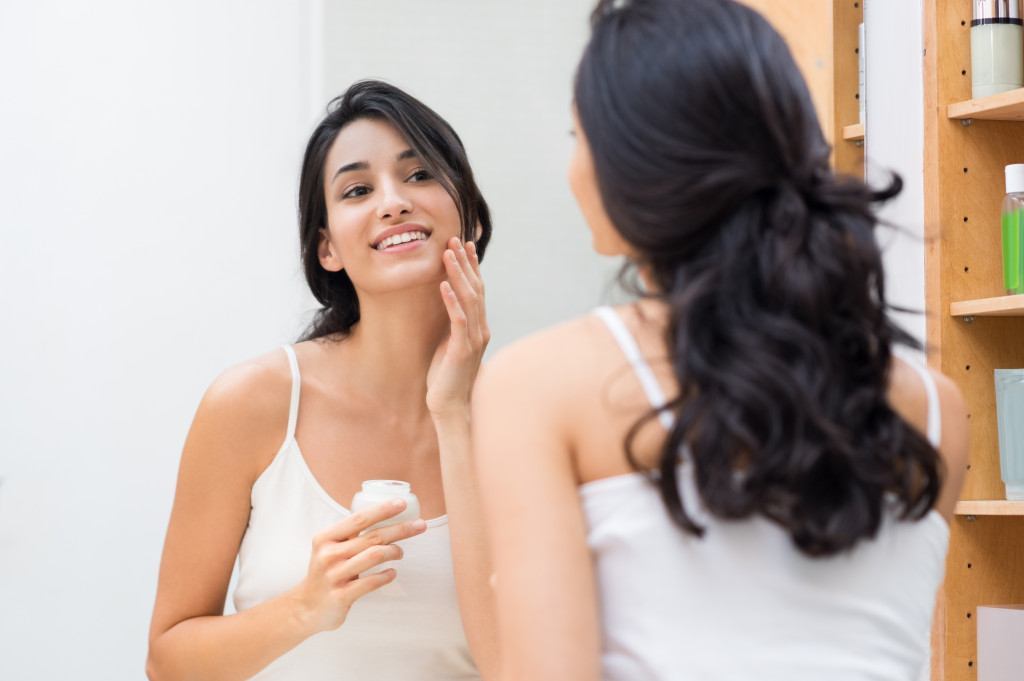 woman looking at the mirror touching her face