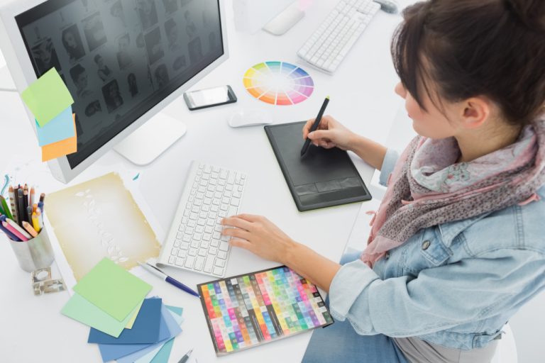 A woman drawing on a graphic tablet in a creative office