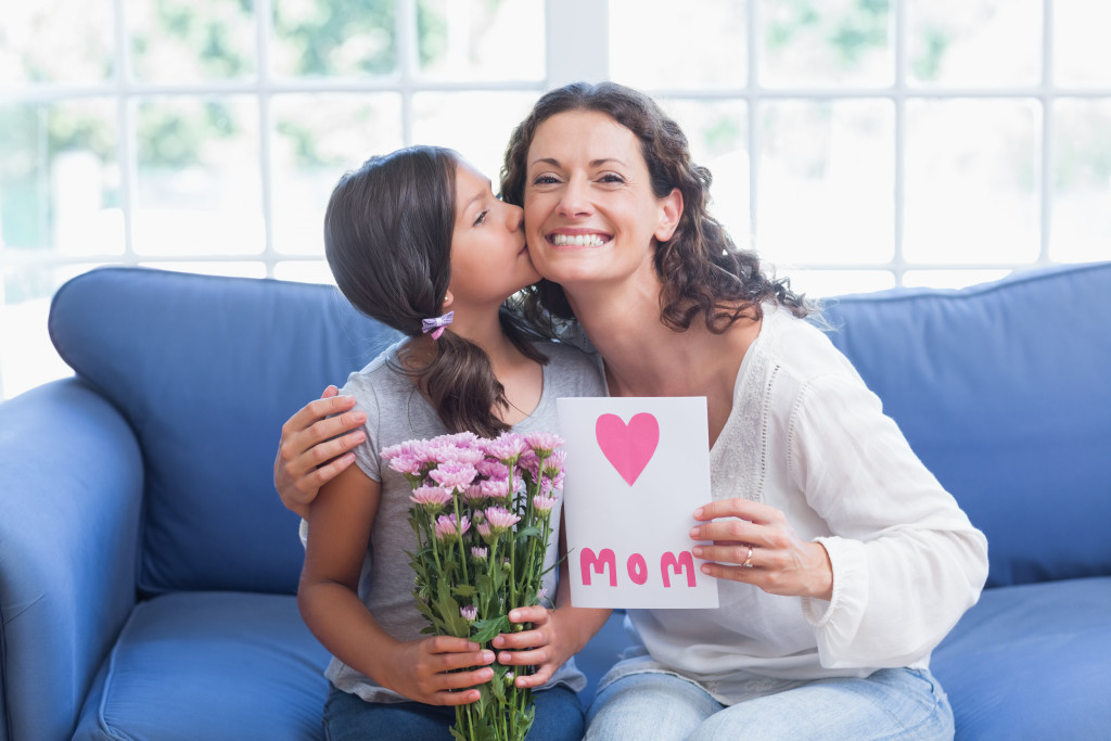 A Little Girl Kissing Mother with flower and letter for mom