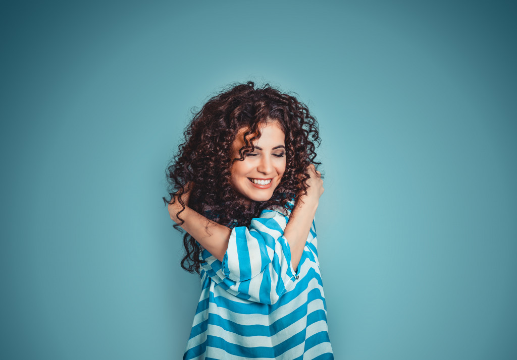 woman hugging herself against blue background