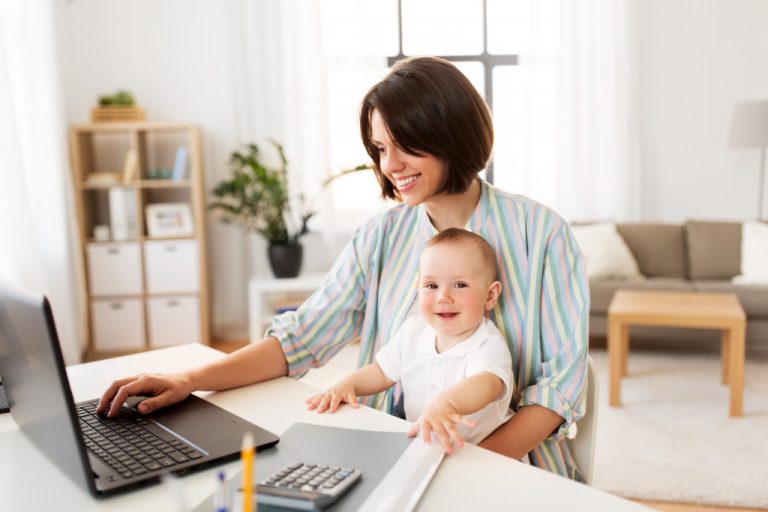 mom working on laptop while carrying baby boy